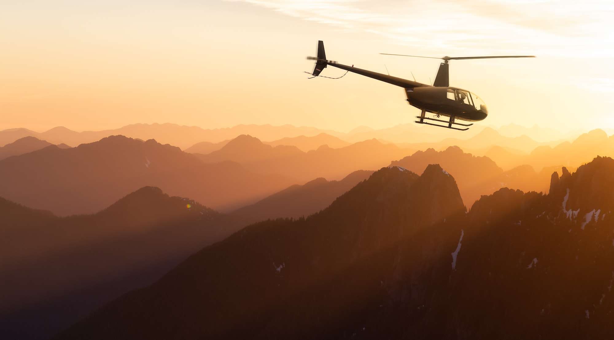 Black Helicopter flying over the Canadian Rocky Mountains