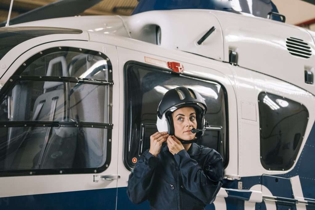 Pilot girl poses with her helicopter wearing helmet